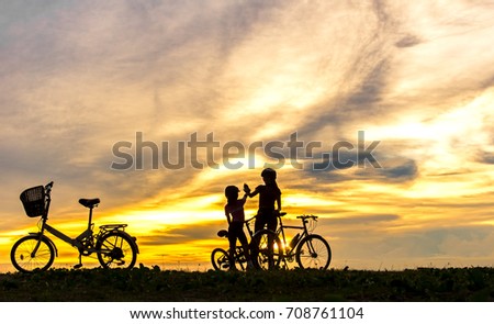Silhouette biker lovely family at sunset over the ocean.  Mom and daughter bicycling at the beach.  Lifestyle Concept.