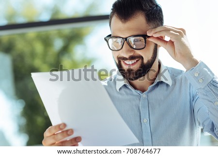 Bearded young man looking at documents and smiling