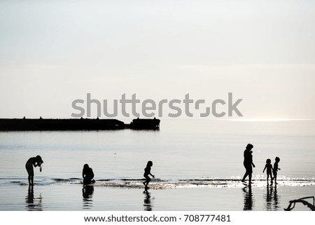 A family with children walks along the shore at sunset