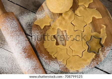 Overhead view of star shape on dough over cutting board by rolling pin at table