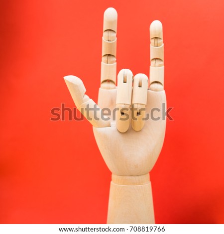 Wooden hand doll make freedom love rock and peace isolated on red background.