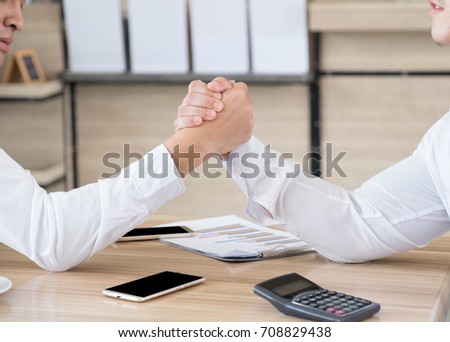 two asian business man arm-wrestle during discussing document about finance on table at meeting time, fight business concept, soft focus background