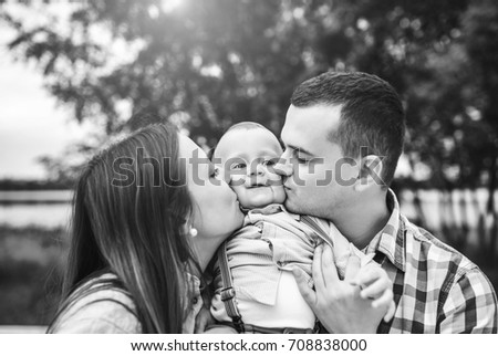 Young happy parents playing with little son outdoor in the park, black and white