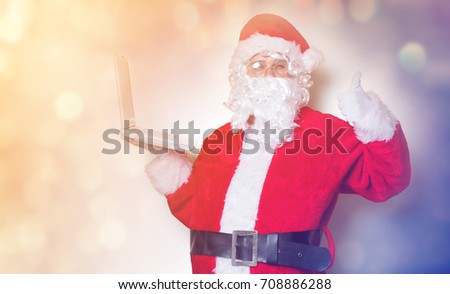 Funny Santa Claus have a fun with laptop on yellow background