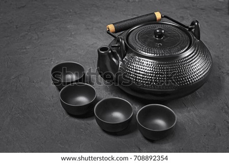 Asian black traditional teapot and teacups for tea ceremony on concrete background