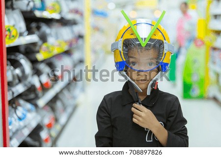 Funny kid with a helmet on his head in supermarket.