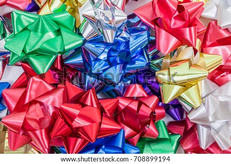 A horizontal photo of a pile of brightly colored and shiny holiday bows