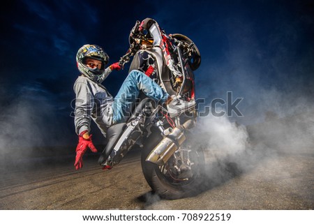 Moto rider making a stunt on his motorbike. Biker doing a difficult and dangerous stunt. Royalty-Free Stock Photo #708922519