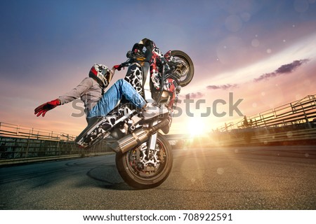 Moto rider making a stunt on his motorbike. Biker doing a difficult and dangerous stunt. Royalty-Free Stock Photo #708922591
