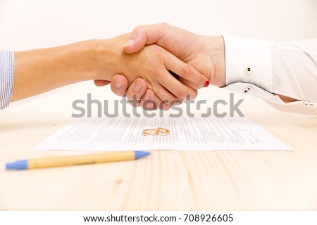 Closeup of a young man an a young woman shaking hands after signing a prenuptial agreement Royalty-Free Stock Photo #708926605
