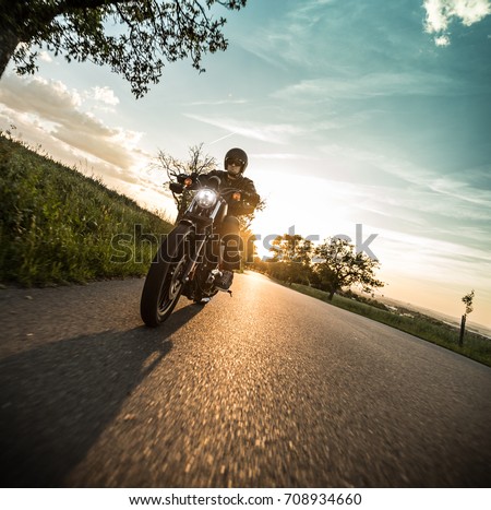 Man riding sportster motorcycle on countryside during sunset. Royalty-Free Stock Photo #708934660