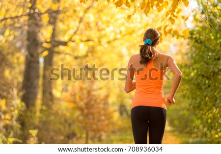 Young brunette woman running in autumn forest. Lifestyle and sport photo of healthy style. Outdoor and nature fitness exercise.