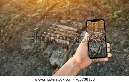 man taking a picture of shish kebab using a smartphone, point of view shot