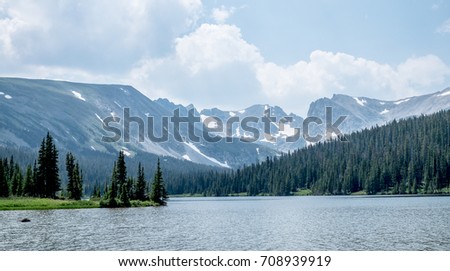 A view from the lakeside in Colorado with pine forest and Rocky Mountains in the background