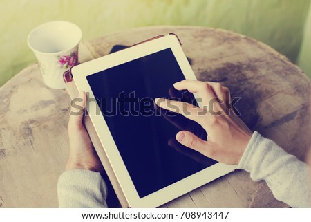 White tablet with a blank screen in the hands on wooden table