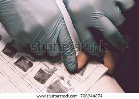 The investigator takes fingerprints from the suspect in the crime. Investigation is a crime. Crime. Royalty-Free Stock Photo #708944674