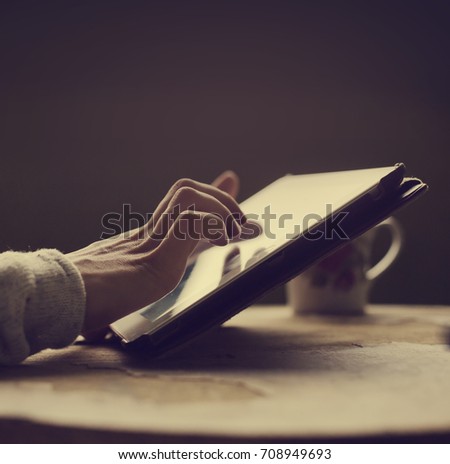 White tablet with a blank screen in the hands on wooden table