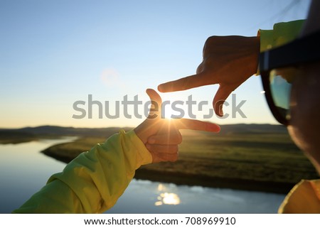 Human hands making a frame sign over sunset sky 