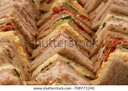 Platter of a selection of sandwiches cut into triangles and lined up on a tray. Royalty-Free Stock Photo #708973240