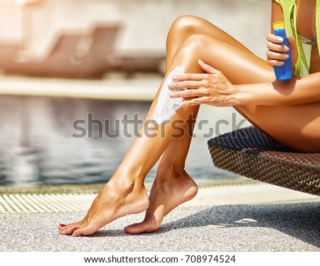 Woman applying sunscreen on legs - close up