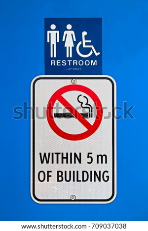 A no smoking within 5m of building sign at a reststop washroom.