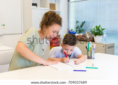 teacher woman drawing with child boy in a classroom