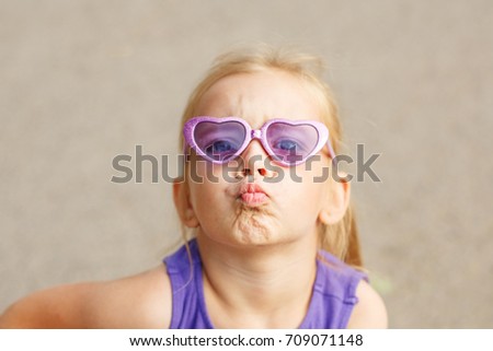 A nice little girl in sunglasses. Portrait of a child. She sends an air kiss