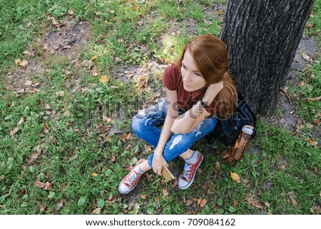 Young successful woman doing selfie in a park in nature. Hipster girl sitting on social networks and read messages.
