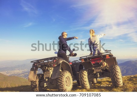 Couple driving off-road with quad bike or ATV