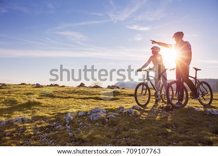Biker couple with mountain bike pointing in distance at countryside Royalty-Free Stock Photo #709107763