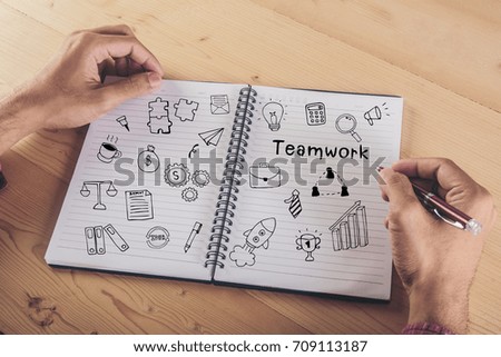 Close up of businessman hands writing on notebook with business doodle icon. Business concept.