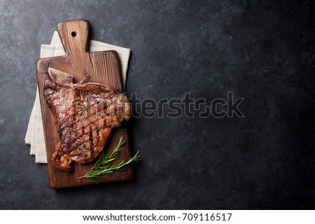 Grilled T-bone steak on stone table. Top view with copy space Royalty-Free Stock Photo #709116517