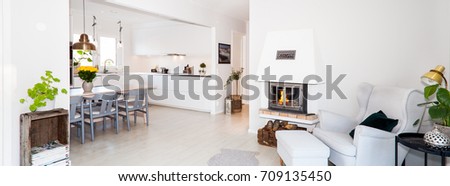 banner of a clean stylish living room interior with lit fire in fireplace and kitchen in the background