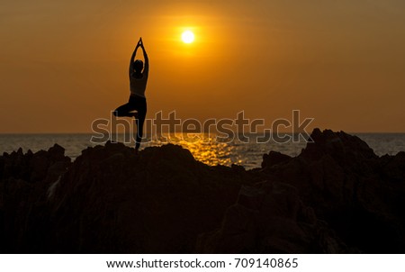 Silhouette young woman lifestyle exercising vital meditate and practicing yoga on the beach at sunset.  Healthy Concept.