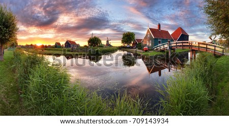 Panorama landscape windmills on water canal in village. Colorful spring sunset in Netherlands, Europe  Royalty-Free Stock Photo #709143934