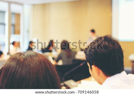 Abstract blurred image of education people and business people sitting in seminar room for profession seminar and the speaker is presenting new technology and idea sharing activity. education concept