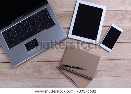 Smartphone and a tablet and a laptop isolated on the wooden background