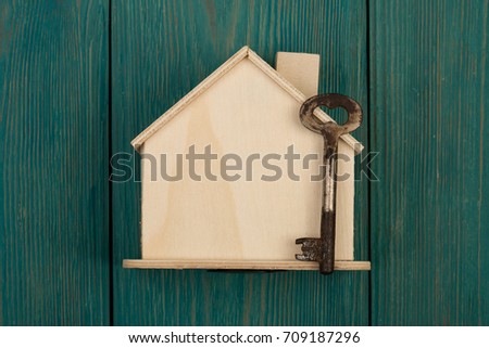 privacy concept - little blank house and key on blue wooden desk
