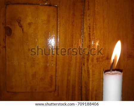 White candle in front of wooden door.