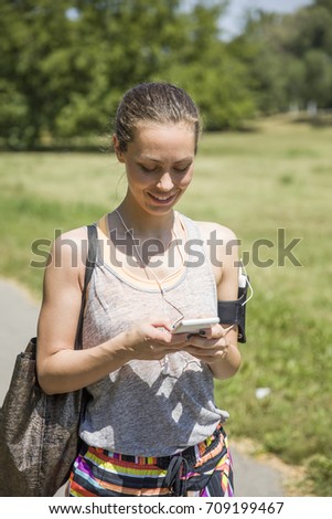 Female runner listening music outdoor at sunny day