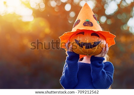 Happy Halloween! Cute little child with a pumpkin in the park.