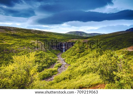 Picturesque landscape of a mountain waterfall and traditional nature of Iceland.