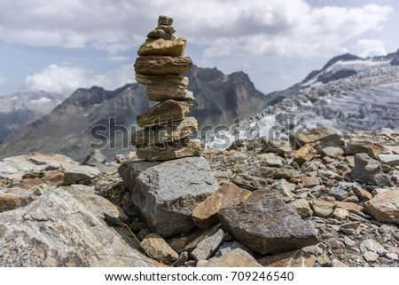 A beautiful cairn with mountains and a glacier in the background in the alps of switzerland. 