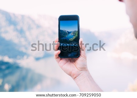 Close up of male or female hand holding futuristic smartphone with photography application, making photo of touristic destination, millennial and hipster for social media