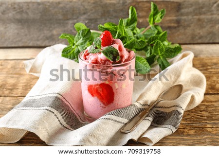 Glass with tasty strawberry yogurt ice cream on wooden table