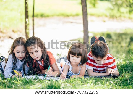 group of little girls and boy painting with paintbrush and colorful paints