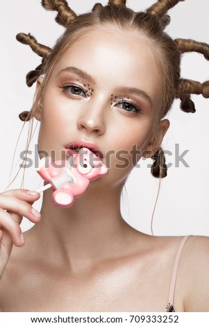 Portrait of beautiful cute girl with fun hairstyle and creative art make-up. Beauty face. Photo taken in the studio.