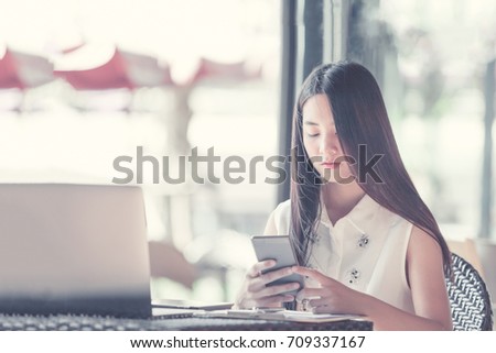 Student woman  touching smartphone screen and smiling. Open space on coffee shop or cafe background. Vintage or retro style. Film effect.. Education concept .