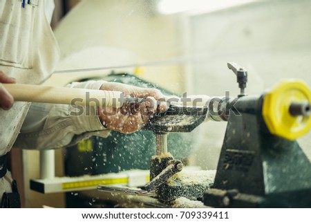 man's hands hold chisel near lathe, man working at small wood lathe, an artisan carves a piece of wood using a manual lathe
