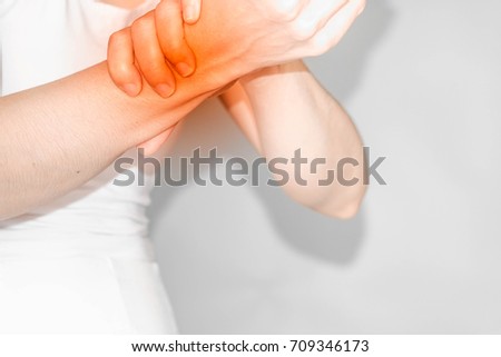 woman with wrist pain. Female holding hand to spot of 
Sore wrist. Concept photo with read spot indicating location of the pain.